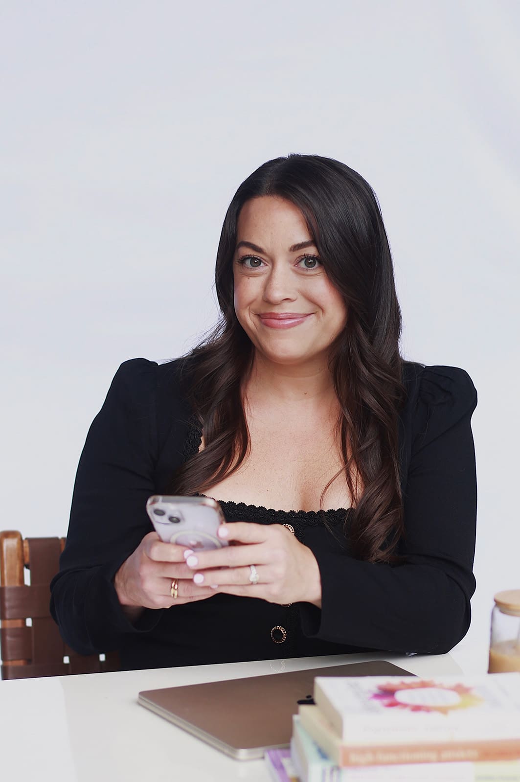 Therapist, Emily Austin, soft smiling at the camera while holding a cell phone in her hands.